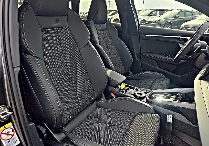 Vue intérieure côté conducteur de l’Audi A3 Sportback 2026 avec sièges sport noirs et surpiqûres contrastées.
