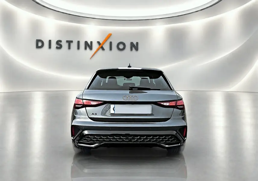 Vue arrière d'une Audi A3 Sportback gris Daytona 2026 dans un showroom lumineux avec logo Distinxion en arrière-plan.