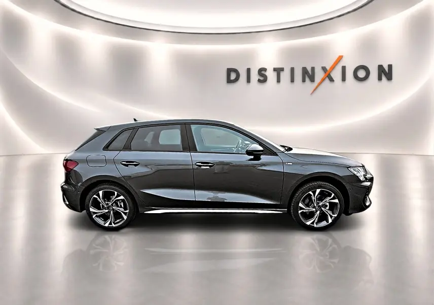 Profil droit d'une Audi A3 Sportback gris Daytona avec jantes alu 18 pouces dans un showroom lumineux.