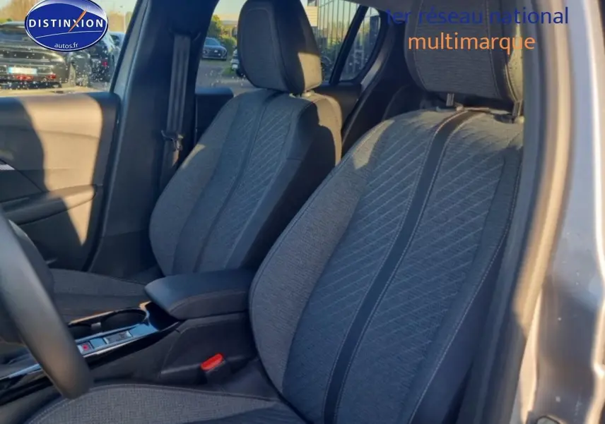 Vue intérieure côté conducteur montrant les sièges tissu gris de la Peugeot 208 1.2 100 Allure 2025.
