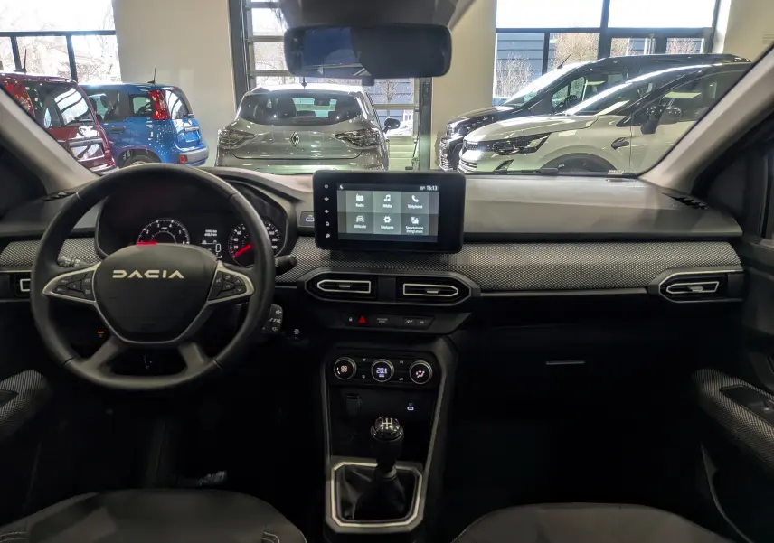 Vue intérieure avant du tableau de bord et volant du Dacia Sandero TCe 90 gris schiste avec écran tactile et boîte manuelle.