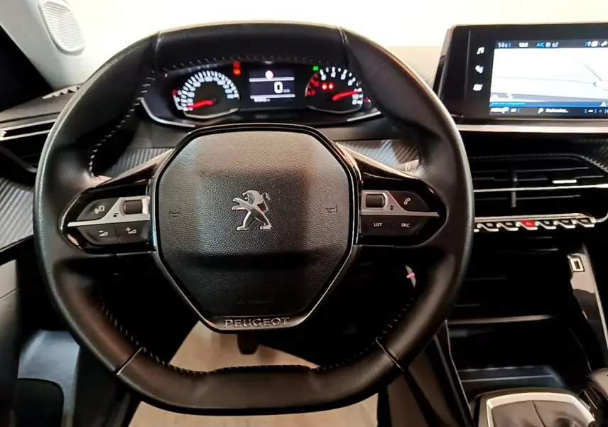 Vue rapprochée du volant cuir noir multifonctions de la Peugeot 2008 avec tableau de bord numérique et écran tactile.