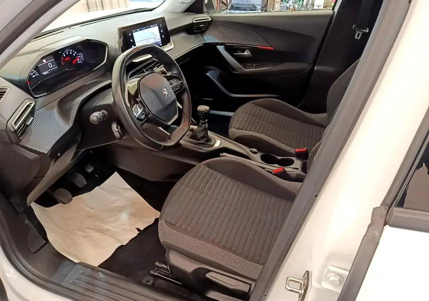Vue intérieure côté conducteur du Peugeot 2008 blanc 2021, volant cuir multifonctions et tableau de bord numérique.