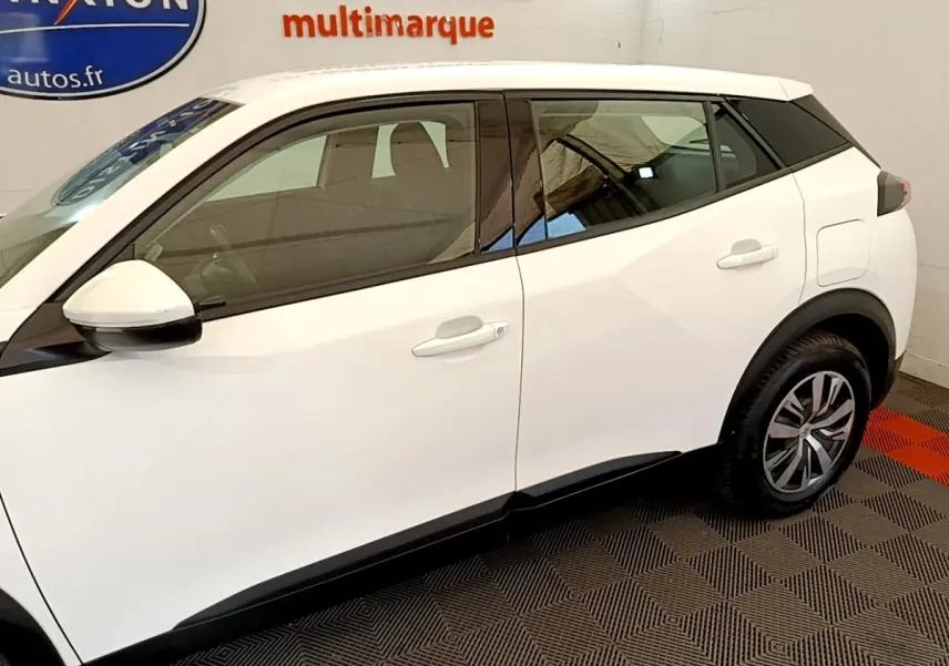 Vue de profil côté gauche d'un Peugeot 2008 blanc avec détails noirs sur les montants et jantes alliage.
