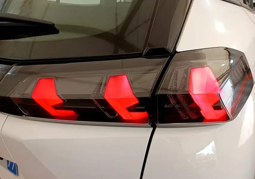 Gros plan sur les feux arrière rouges en forme de griffes du Peugeot 2008 blanc, vue arrière côté droit.