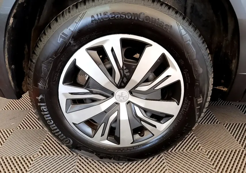 Gros plan sur la roue avant droite d'un Peugeot 2008 blanc, avec jante alliage et pneu Continental AllSeasonContact.
