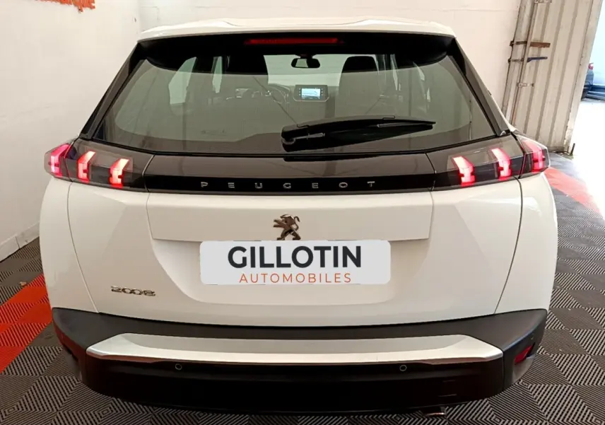 Vue arrière d’un Peugeot 2008 blanc avec feux arrière LED en forme de griffes et logo lion central.