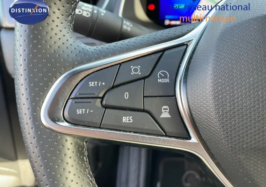 Gros plan sur les commandes au volant en cuir perforé noir de la Renault Symbioz 2025, avec écran digital flou en arrière-plan.