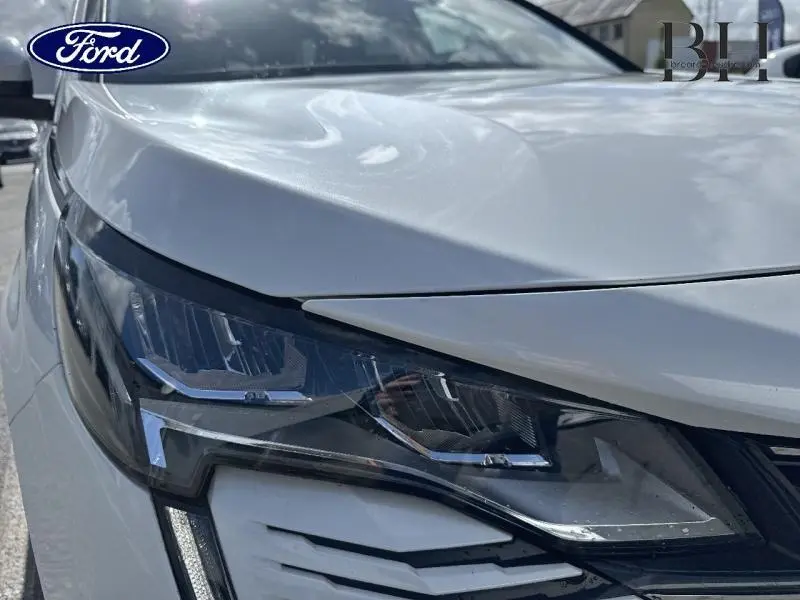 Gros plan sur le phare avant gauche du Peugeot 5008 blanc nacré, soulignant ses lignes modernes et LED.