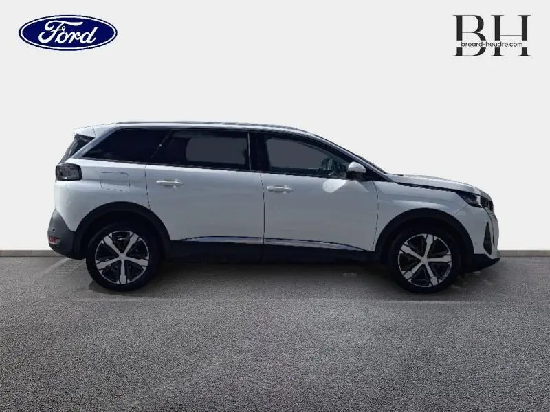 Profil droit d'un Peugeot 5008 blanc nacré 2021 avec vitres arrière surteintées et jantes alliage noires et argentées.