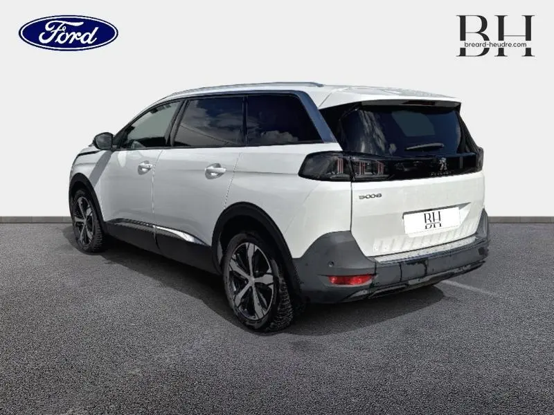 Peugeot 5008 blanc nacré vue 3/4 arrière droit, avec vitres arrière surteintées et jantes alliage noires.