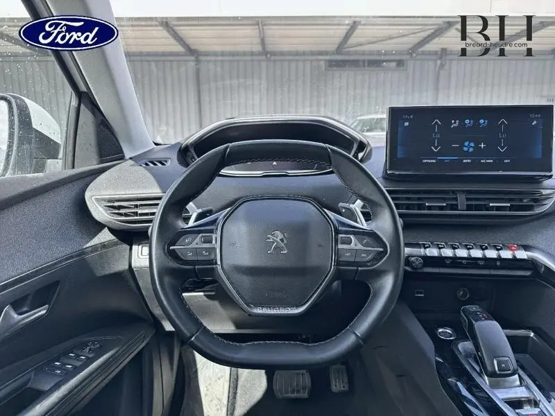 Vue intérieure centrée sur le volant cuir noir du Peugeot 5008 avec tableau de bord et écran tactile visible.