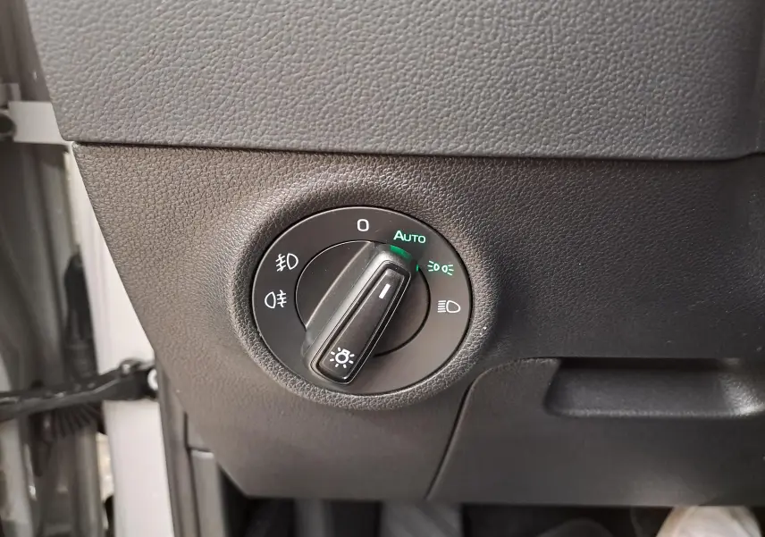 Gros plan sur le bouton de commande des phares du Skoda Karoq 2023 gris perle, avec réglage automatique activé.