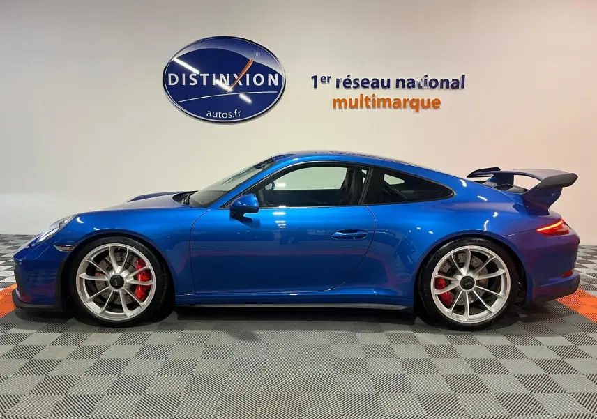 Vue de profil côté gauche d'une Porsche 911 GT3 bleu saphir avec aileron arrière et jantes sport argentées.