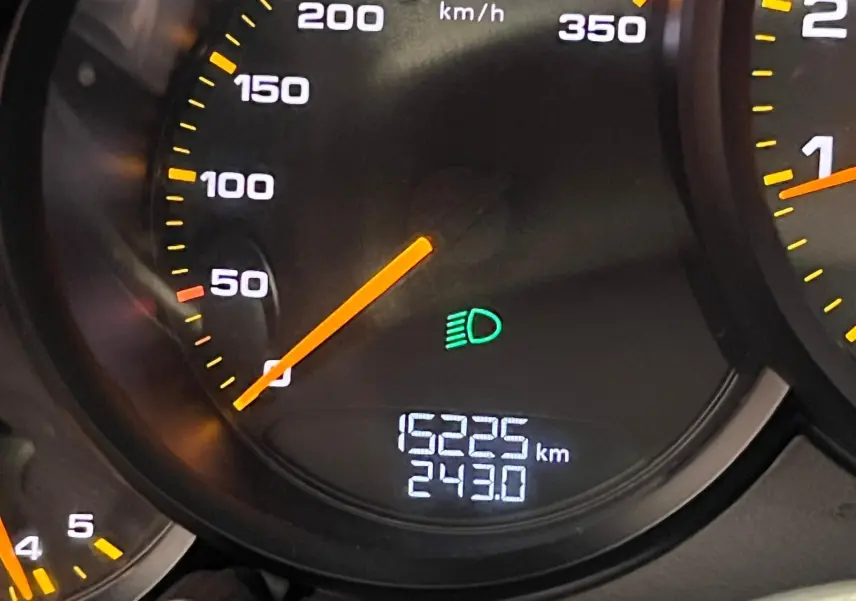 Gros plan sur le compteur de vitesse de la Porsche 911 GT3 affichant 15 225 km et témoin des feux de route allumé.