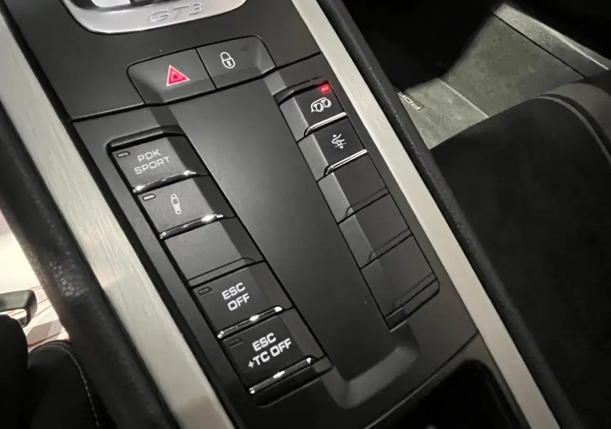 Gros plan sur la console centrale noire et aluminium de la Porsche 911 GT3 bleu saphir, avec boutons sport et GT3 visible.