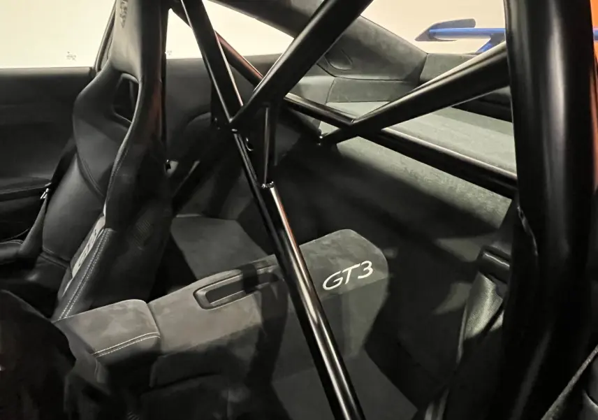 Vue intérieure arrière droite de la Porsche 911 GT3 2018, montrant l'arceau de sécurité et les sièges baquets noirs avec logo GT3.
