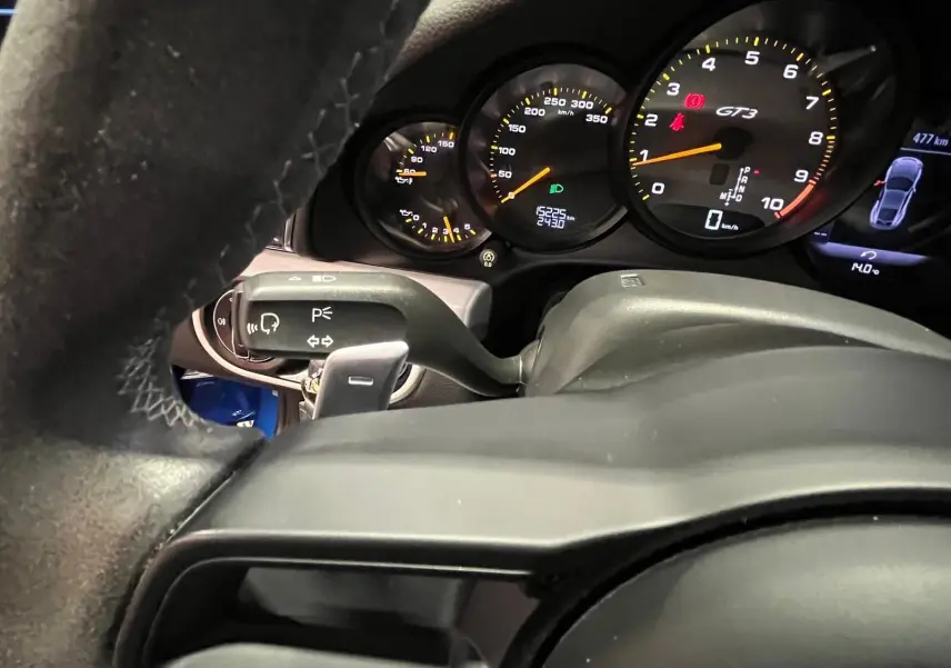 Vue rapprochée du tableau de bord de la Porsche 911 GT3 2018, affichant le compteur et le volant sport en alcantara.