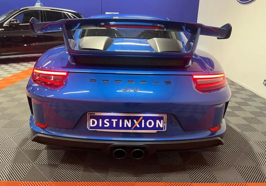 Vue arrière d'une Porsche 911 GT3 bleu saphir avec grand aileron et double sortie d'échappement centrale.