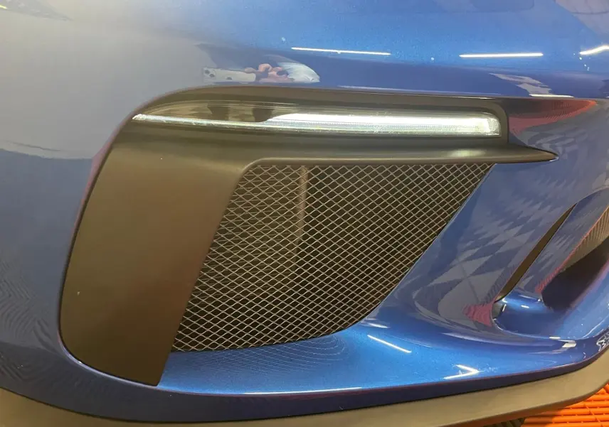 Gros plan sur la prise d'air avant droite et le feu LED d'une Porsche 911 GT3 bleu saphir.