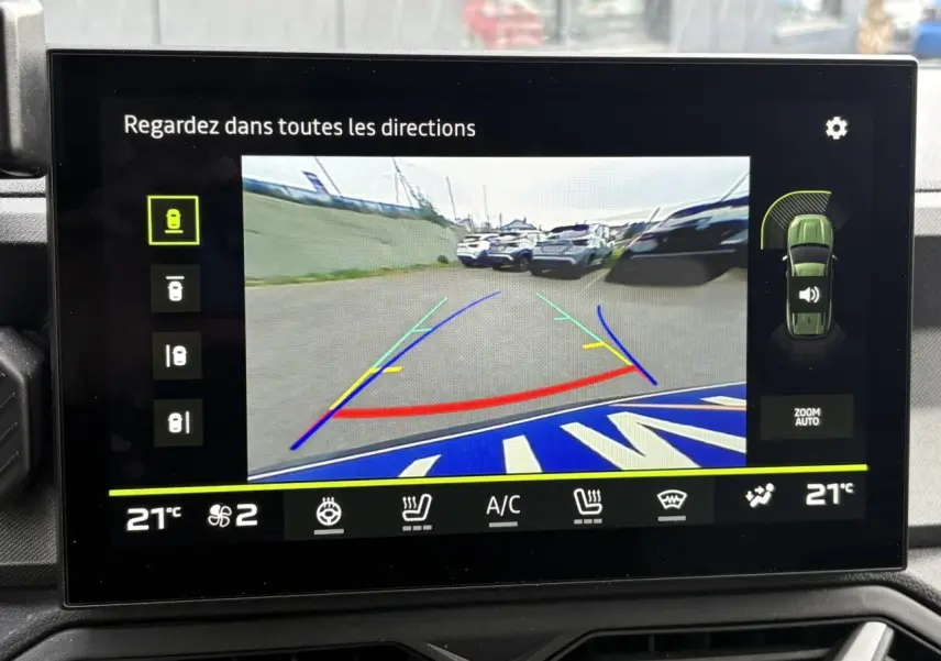 Écran tactile affichant la caméra multivues du Dacia Bigster blanc banquise en marche arrière avec lignes de guidage colorées.