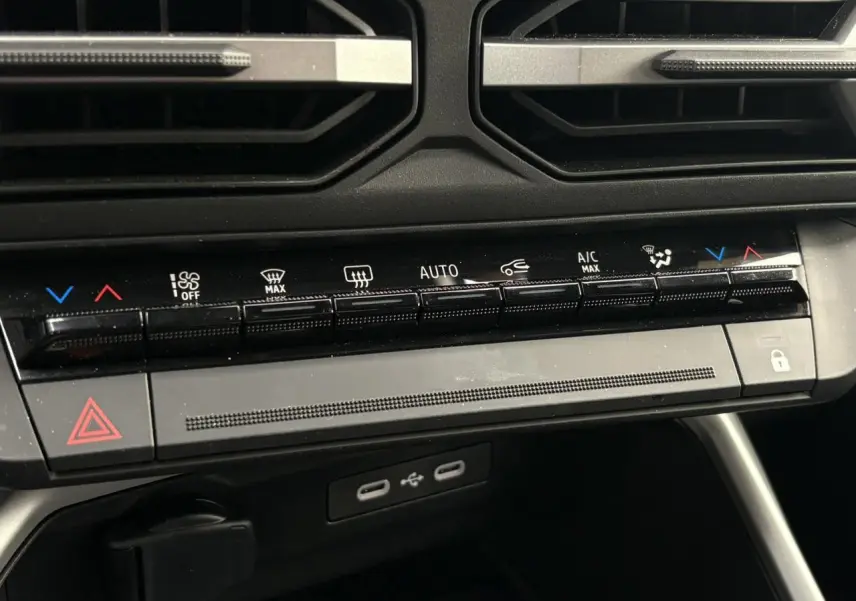 Vue rapprochée de la console centrale du Dacia Bigster blanc, montrant les commandes de climatisation et ports USB.