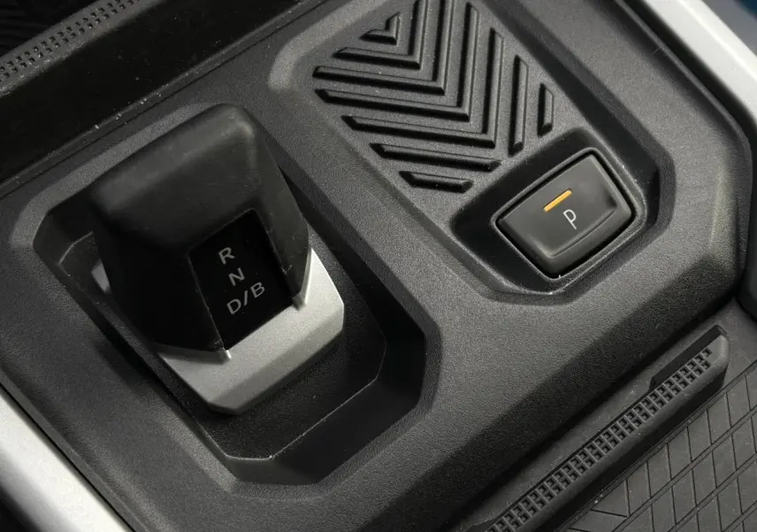 Gros plan sur la commande de boîte automatique et bouton de parking du Dacia Bigster blanc Banquise, intérieur noir.