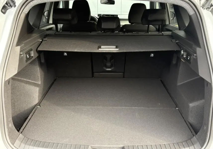 Coffre ouvert du Dacia Bigster blanc Banquise, vue arrière montrant un espace de chargement spacieux et bien fini.