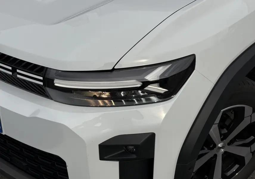 Gros plan sur l'avant droit blanc banquise du Dacia Bigster 2025, avec phare LED et jante alliage diamantée.
