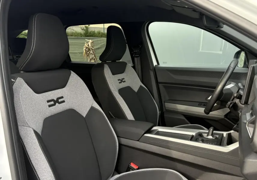 Vue intérieure côté droit montrant les sièges avant gris et noirs avec logo Dacia sur la sellerie du Dacia Bigster 2025.
