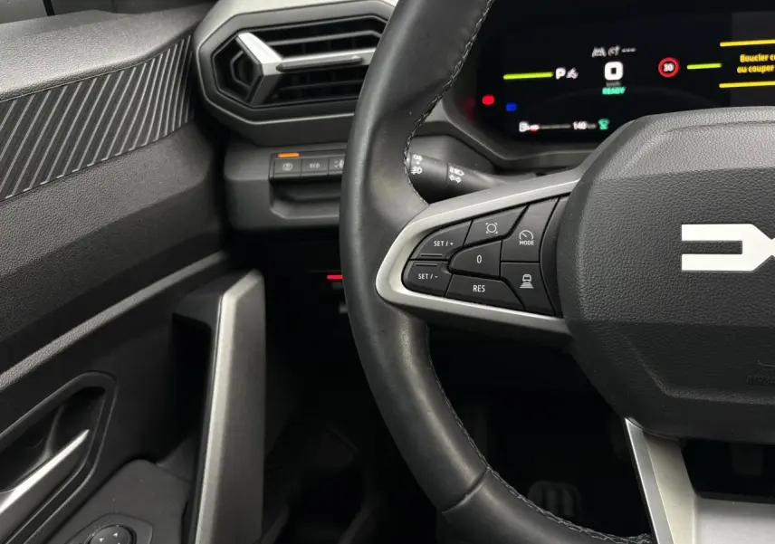 Vue intérieure centrée sur le volant noir du Dacia Bigster 2025, avec commandes multifonctions et tableau de bord numérique.