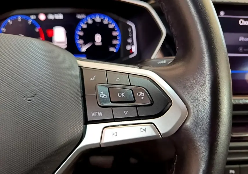 Gros plan sur le volant cuir noir du Volkswagen T-Cross 2022, avec commandes multifonctions et tableau de bord numérique.