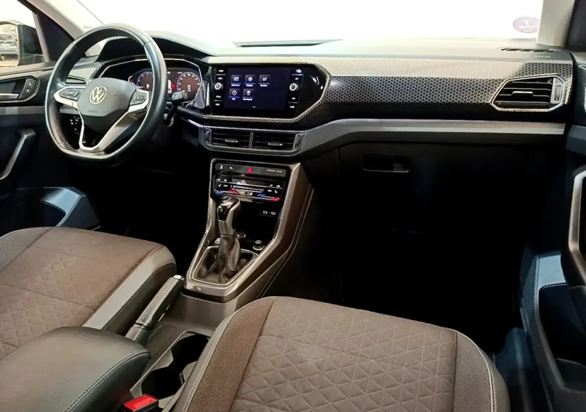 Vue intérieure avant du Volkswagen T-Cross 1.0 TSI 110ch DSG Carat 2022, tableau de bord noir avec écran tactile central.