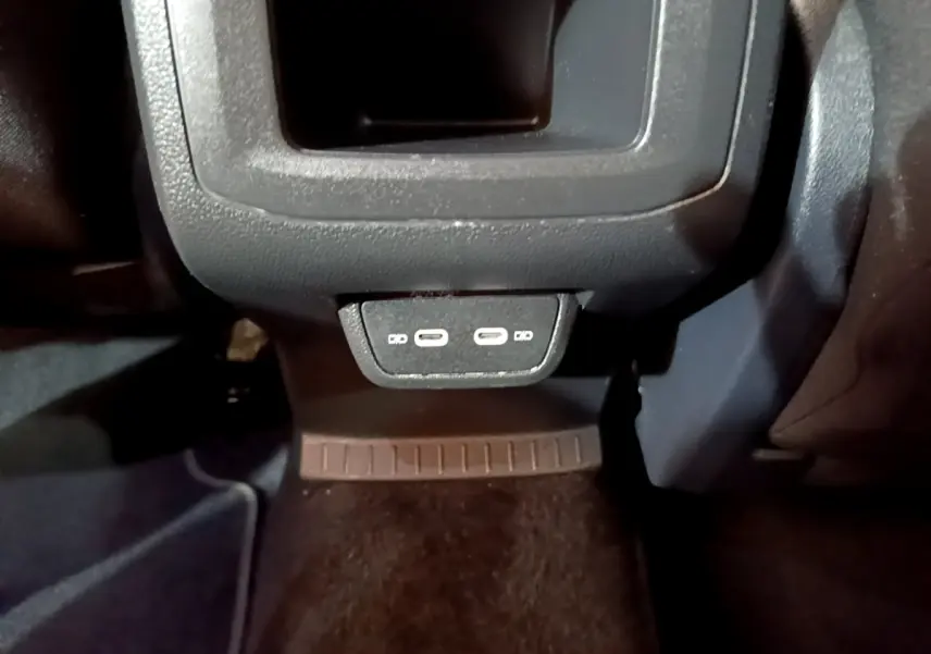 Vue rapprochée des ports USB-C arrière noirs du Volkswagen T-Cross 2022, côté passager, avec moquette sombre.