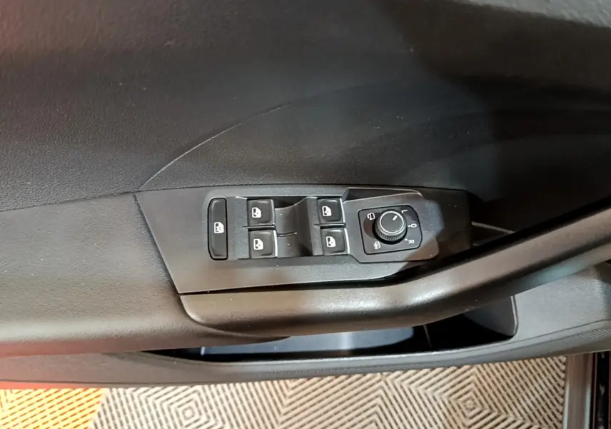 Gros plan sur la commande des vitres et réglage des rétroviseurs côté conducteur d’un Volkswagen T-Cross noir.