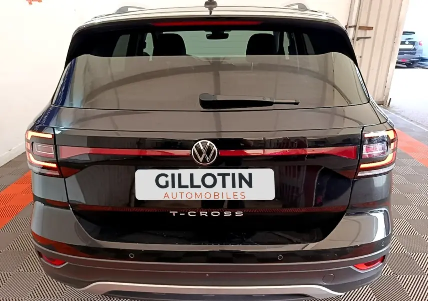 Vue arrière du Volkswagen T-Cross noir 2022 avec feux LED et logo central visible dans un garage.
