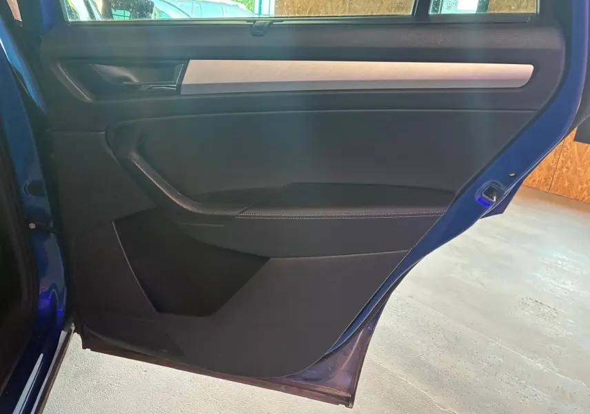 Vue intérieure de la porte arrière gauche d’un Skoda Kodiaq bleu 2023, avec garniture noire et insert décoratif clair.
