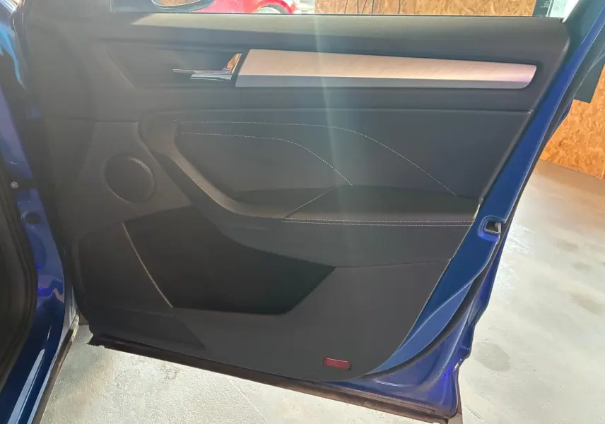 Vue intérieure de la porte avant gauche d’un Skoda Kodiaq bleu 2023, avec garniture noire et insert décoratif clair.