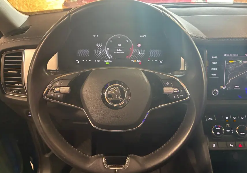 Vue intérieure centrée sur le volant noir du Skoda Kodiaq 2023 avec tableau de bord digital et écran tactile GPS.