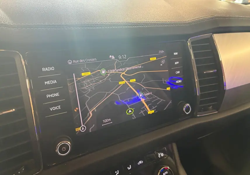 Écran tactile central du Skoda Kodiaq 2023 montrant la navigation GPS, avec commandes multimédia et climatisation visibles.