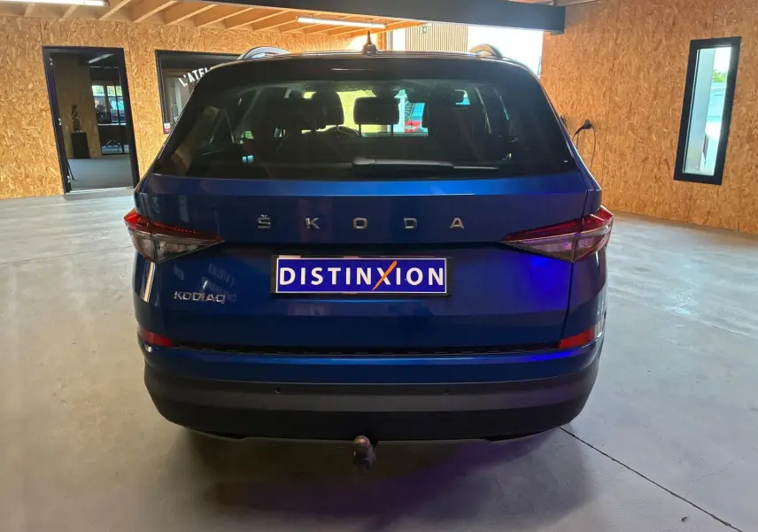 Vue arrière d'un Skoda Kodiaq bleu 2023 avec attelage et logo ŠKODA bien visible en intérieur.
