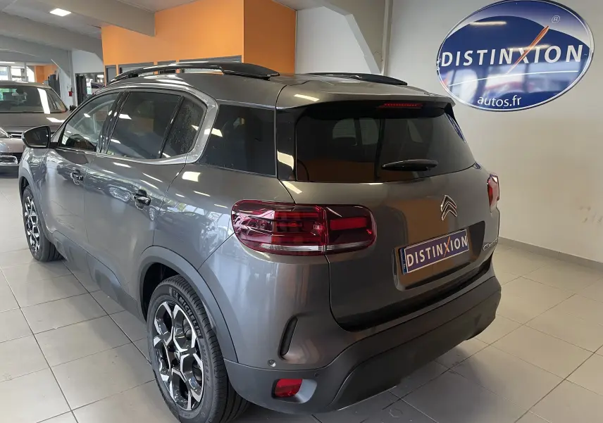 Vue 3/4 arrière droite d'un Citroën C5 Aircross hybride gris platinium avec jantes alliage biton et vitres arrière surteintées.