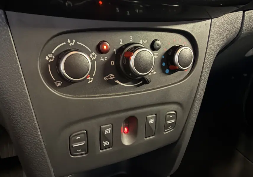 Vue rapprochée des commandes de climatisation et des boutons de réglage du tableau de bord d’une Dacia Sandero Stepway bleu 2019.