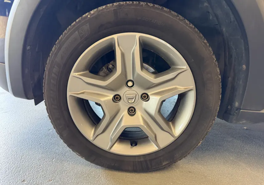 Gros plan sur la roue avant gauche d'une Dacia Sandero Stepway bleu 2019 avec jante alliage à cinq branches.