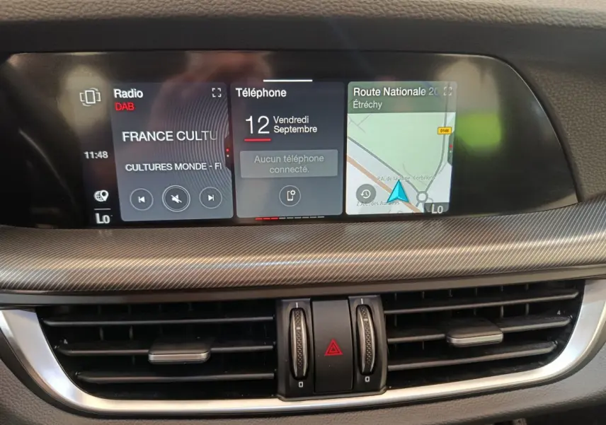 Tableau de bord de l'Alfa Romeo Stelvio 2024 avec écran tactile central affichant radio, téléphone et navigation.