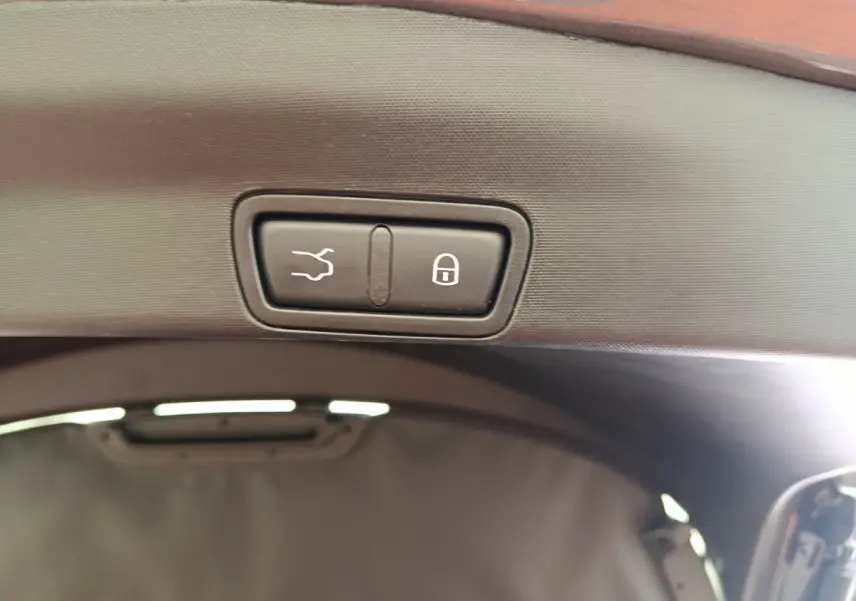 Gros plan sur les boutons d'ouverture et de verrouillage du coffre du coffre d'un Alfa Romeo Stelvio gris foncé.