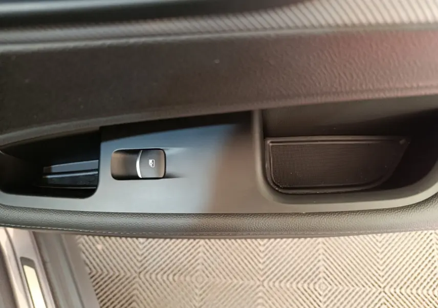 Gros plan sur le bouton de commande de la vitre côté gauche de l'Alfa Romeo Stelvio gris foncé, intérieur noir.