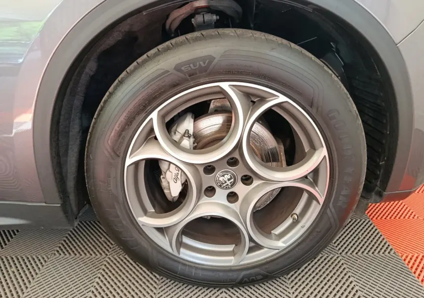 Gros plan sur la roue avant droite gris foncé de l'Alfa Romeo Stelvio 2.2 TD 160 AT8 Sprint avec jante distinctive à cinq cercles.