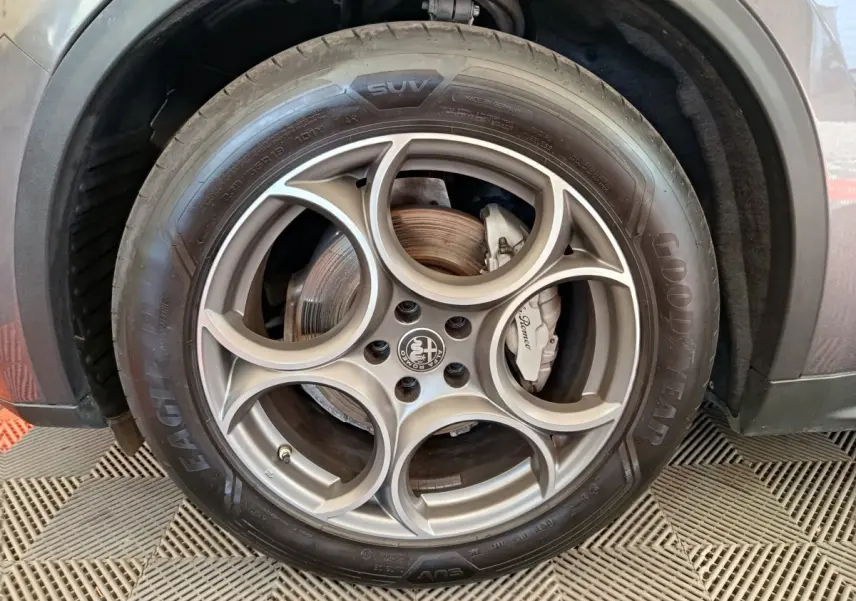 Gros plan sur la roue avant droite gris foncé de l'Alfa Romeo Stelvio avec jante en alliage à cinq cercles distinctifs.