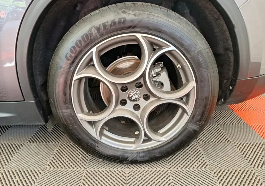 Vue rapprochée de la roue arrière droite d’un Alfa Romeo Stelvio gris foncé, soulignant l’arche de roue et le pneu.